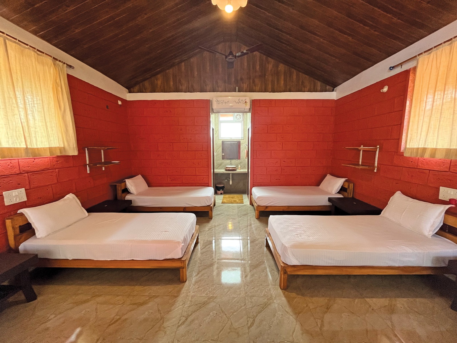 Dormitory interior with distinctive red laterite walls at Mitraay Resort