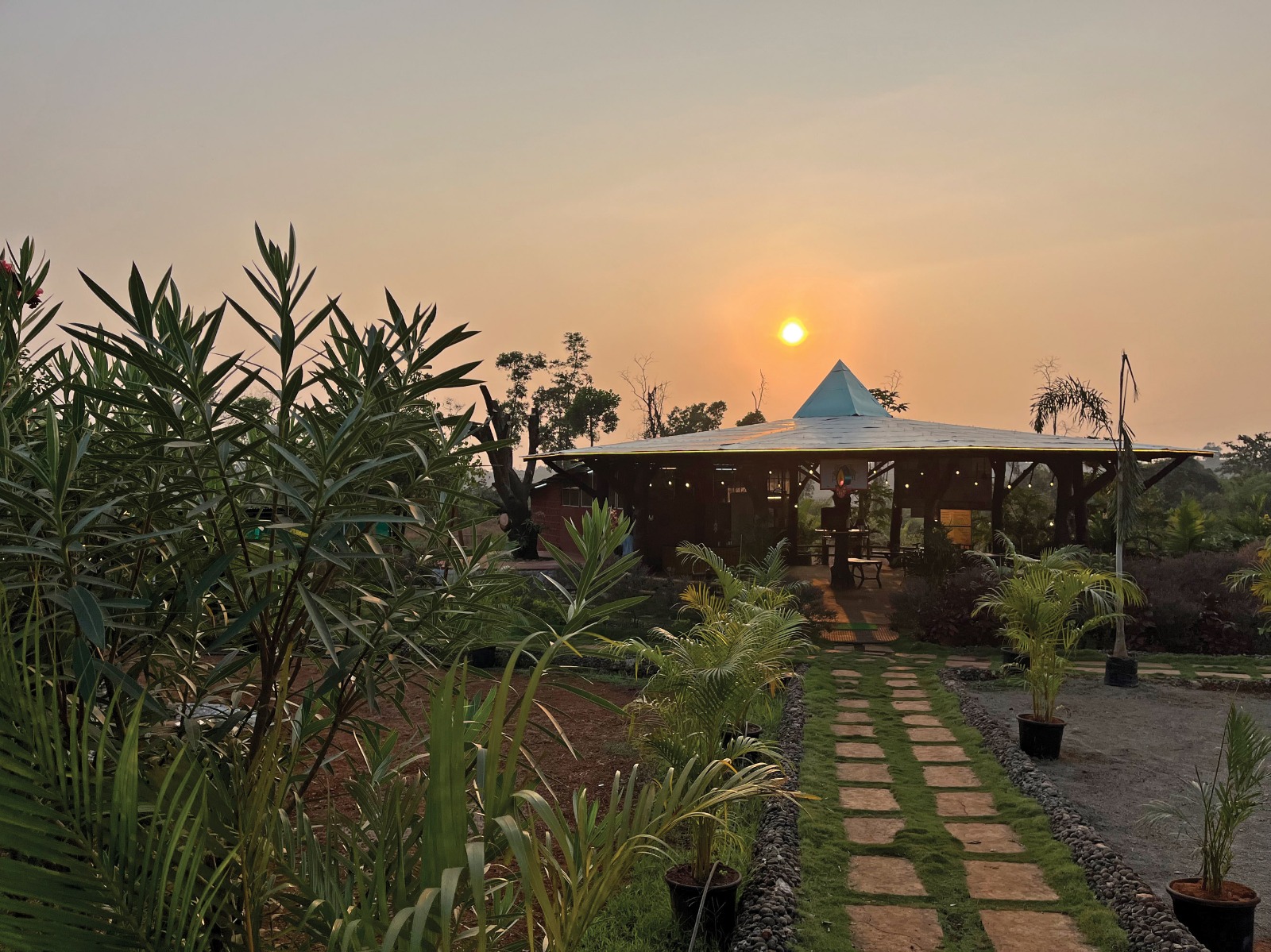 Open pavilion and garden at golden hour at Mitraay Agro Resort